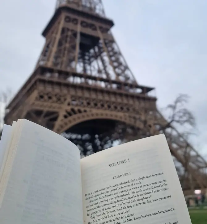 Person reading a book in front of the Eiffel Tower